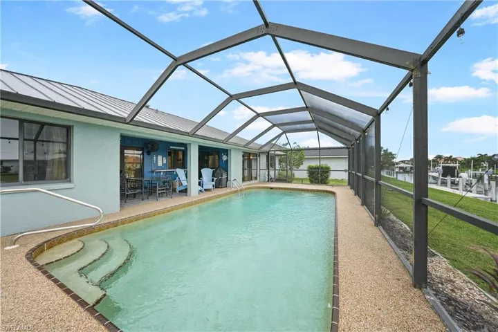 Outdoor pool featuring a sunroom, a lanai, a water view, and a patio area