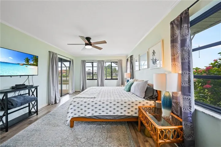 Bedroom featuring crown molding, access to exterior, wood finished floors, and a ceiling fan