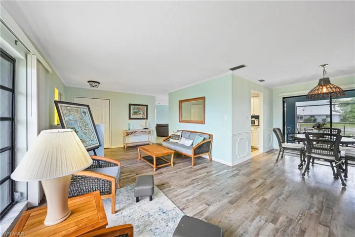 Living room with healthy amount of natural light, ornamental molding, and light wood-style floors