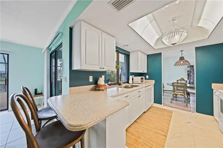 Kitchen with pendant lighting, white cabinetry, a kitchen bar, a peninsula, and ornamental molding