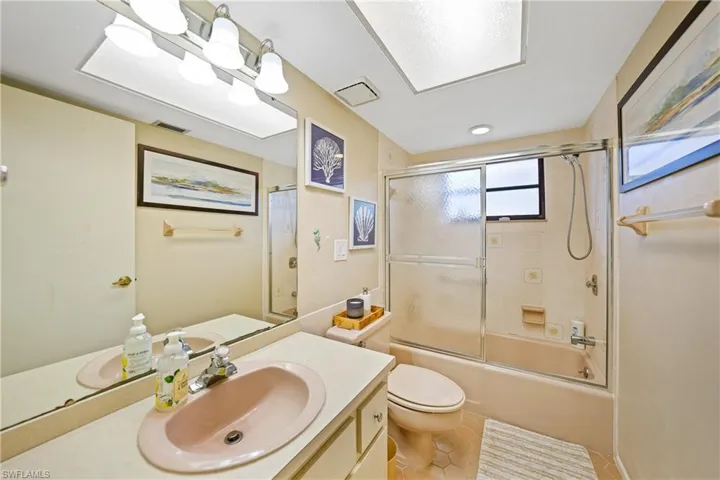 Bathroom featuring vanity, combined bath / shower with glass door, and light tile patterned flooring