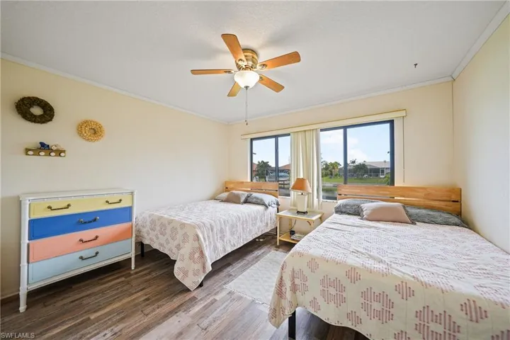 Bedroom with crown molding, wood finished floors, and a ceiling fan