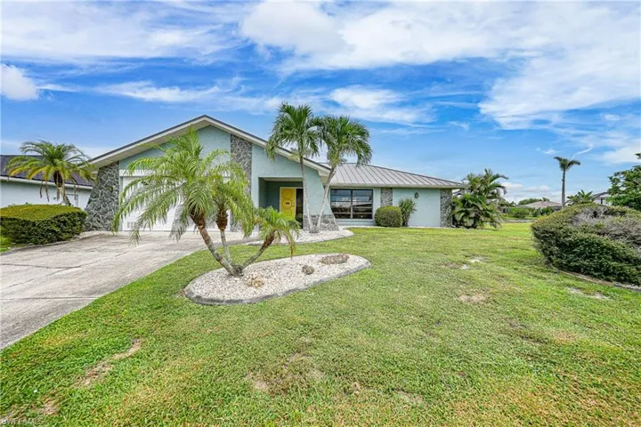 Mid-century modern home featuring a standing seam roof, driveway, stucco siding, a metal roof, and a front lawn