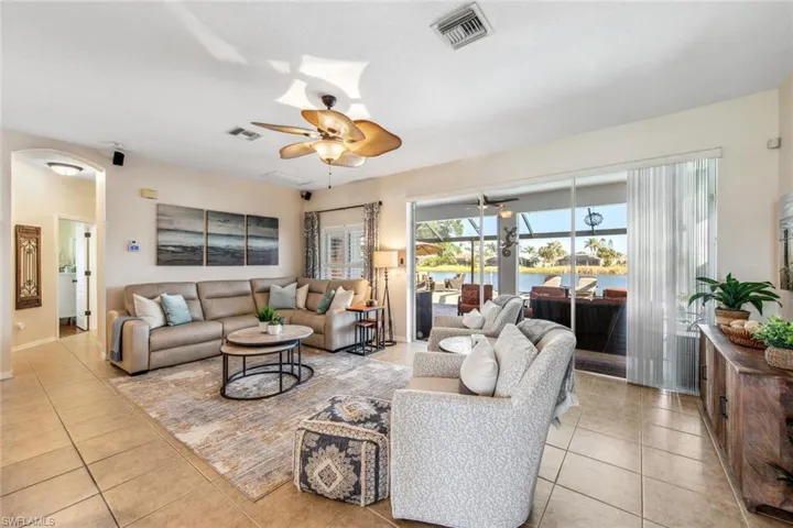 Living room with a ceiling fan, light tile patterned floors, and visible vents