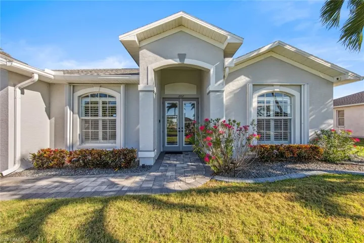 Property entrance with a lawn, stucco siding, and french doors