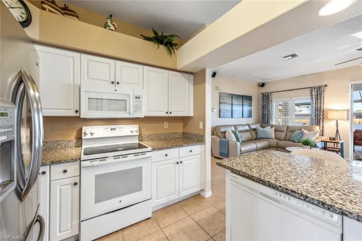 Kitchen with white appliances, open floor plan, white cabinets, and light tile patterned floors