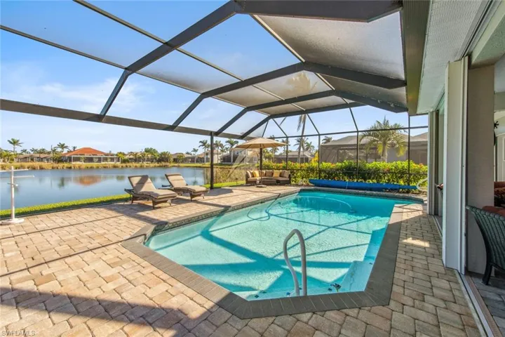 Pool featuring glass enclosure, a water view, and a patio area