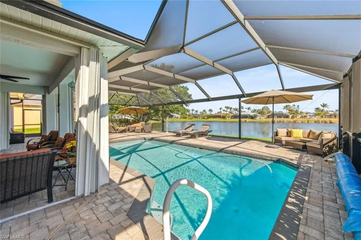 Outdoor pool featuring a water view, glass enclosure, ceiling fan, outdoor lounge area, and a patio area