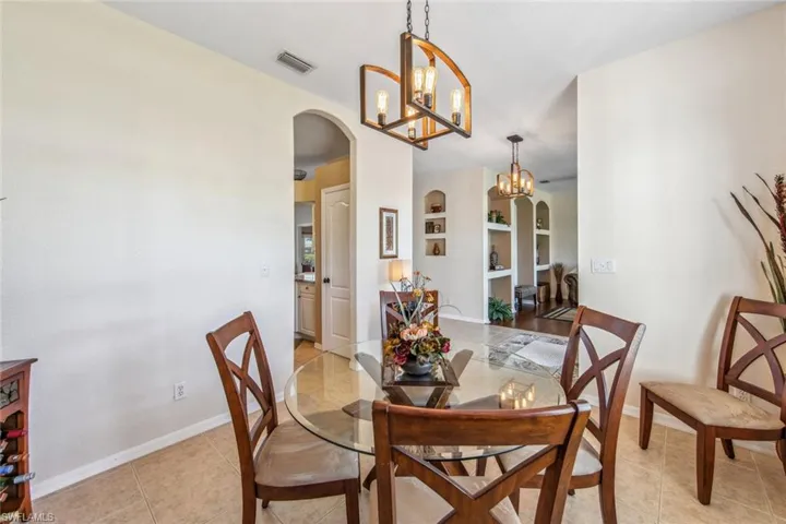 Dining area featuring built in shelves, baseboards, visible vents, arched walkways, and an inviting chandelier