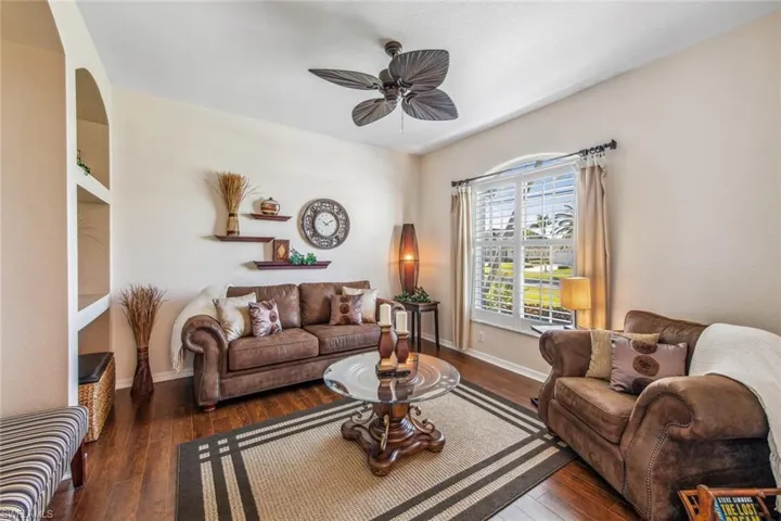 Living room with hardwood / wood-style floors, a ceiling fan, and baseboards