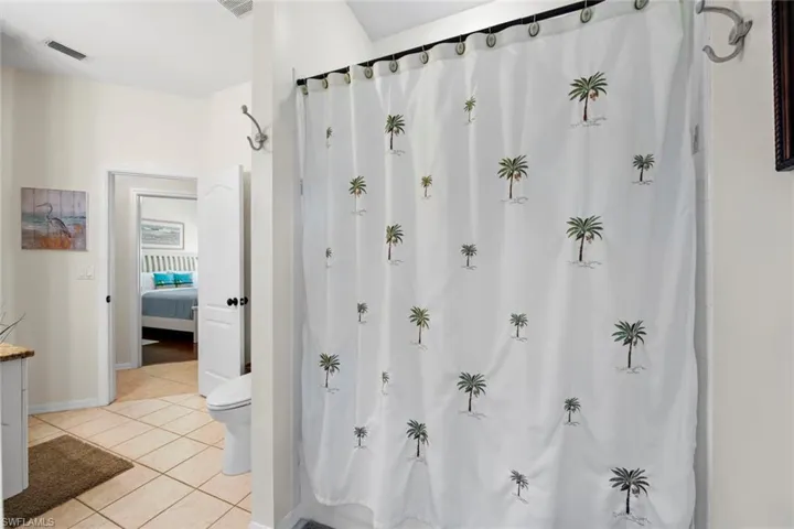 Ensuite bathroom with visible vents, baseboards, connected bathroom, toilet, and tile patterned flooring