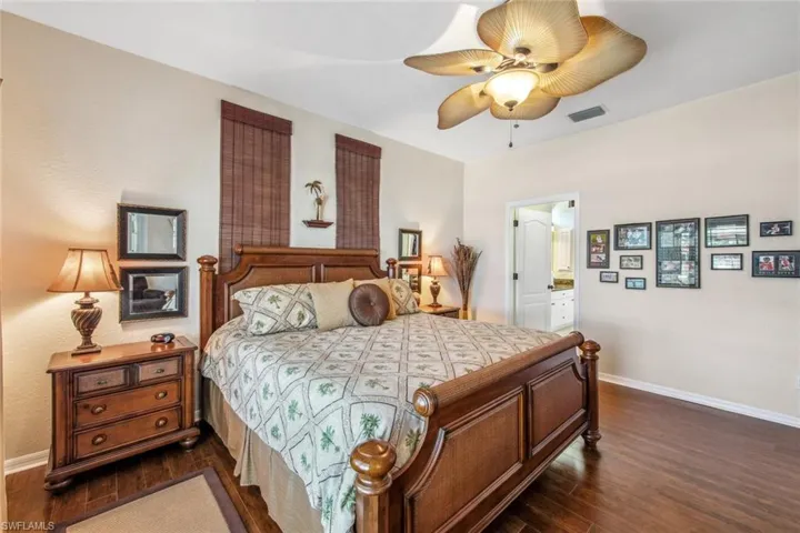Bedroom featuring baseboards, dark wood-style flooring, ensuite bathroom, and visible vents