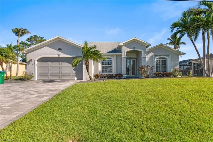 Ranch-style house with stucco siding, french doors, driveway, a front yard, and a garage