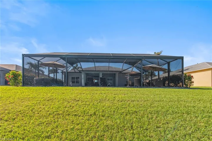 Back of house featuring a lawn and a lanai