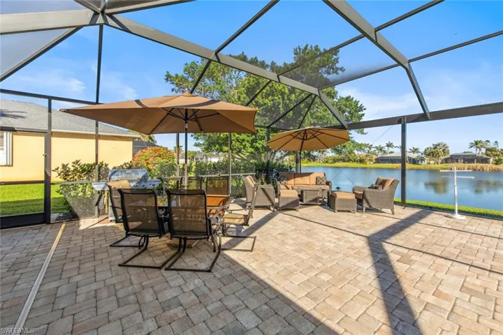 View of patio with glass enclosure, outdoor dining space, an outdoor hangout area, and a water view