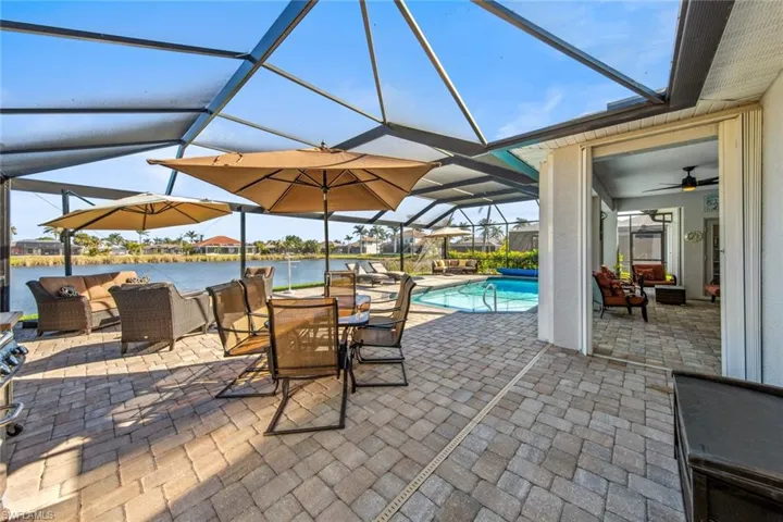 View of patio / terrace with glass enclosure, an outdoor living space, a water view, and an outdoor pool