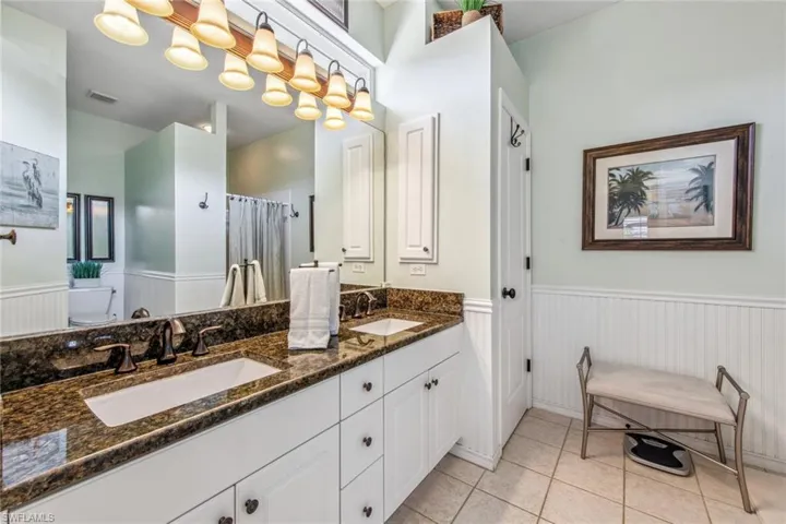 Full bathroom with a sink, tile patterned floors, and wainscoting