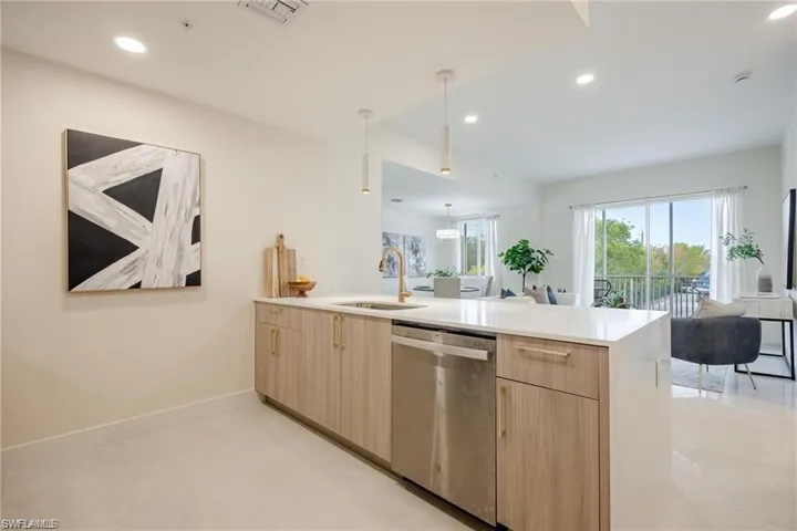 Kitchen with a peninsula, stainless steel dishwasher, light brown cabinetry, open floor plan, and light countertops