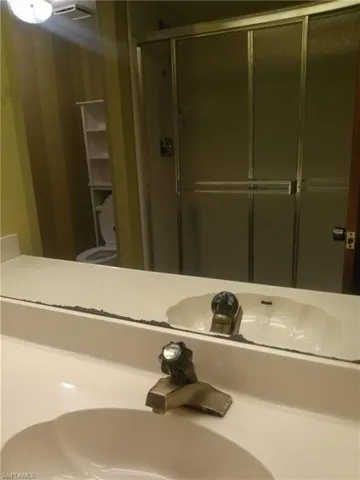 Bathroom with a shower with door, sink, and toilet