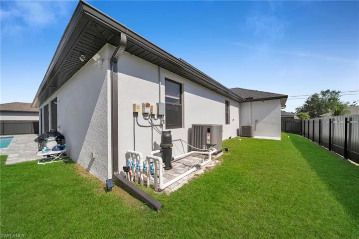Back of property featuring central AC unit, a lawn, and a patio
