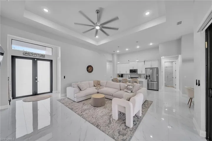 Living room with a tray ceiling, french doors, and ceiling fan
