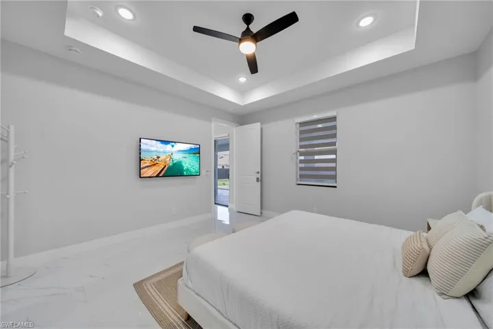Bedroom with a raised ceiling and ceiling fan