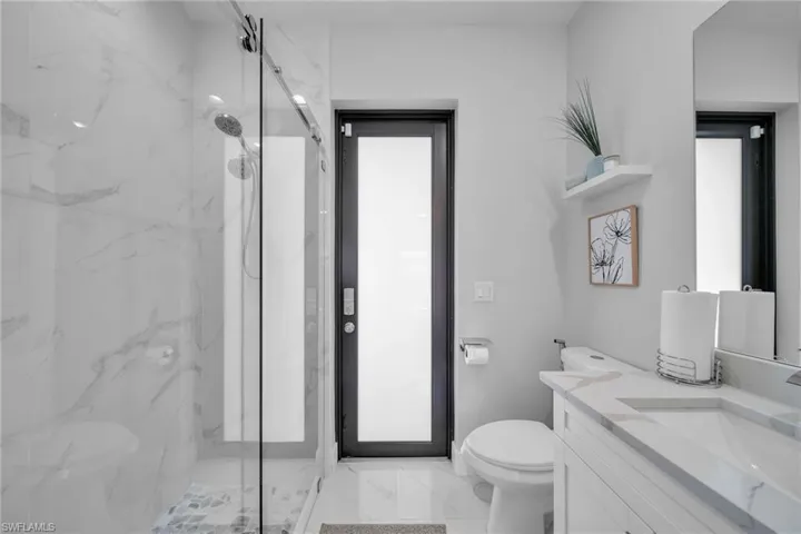 Bathroom with a shower with door, vanity, and toilet