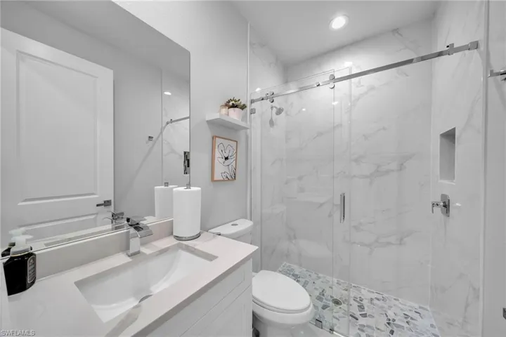 Bathroom with vanity, a shower with shower door, and toilet