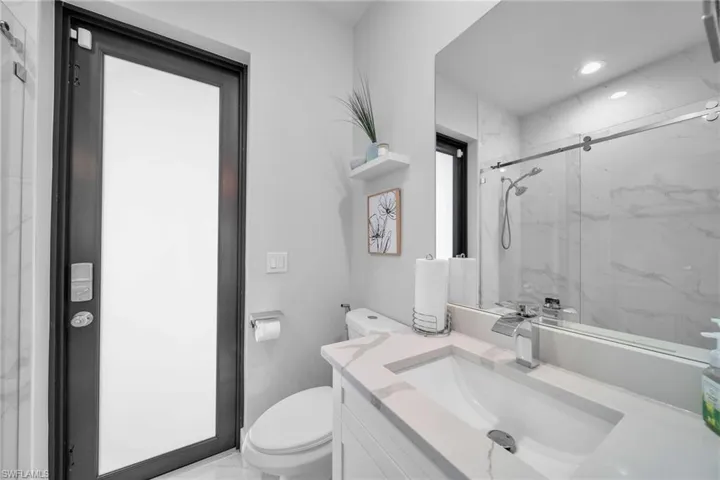 Bathroom featuring vanity, an enclosed shower, and toilet
