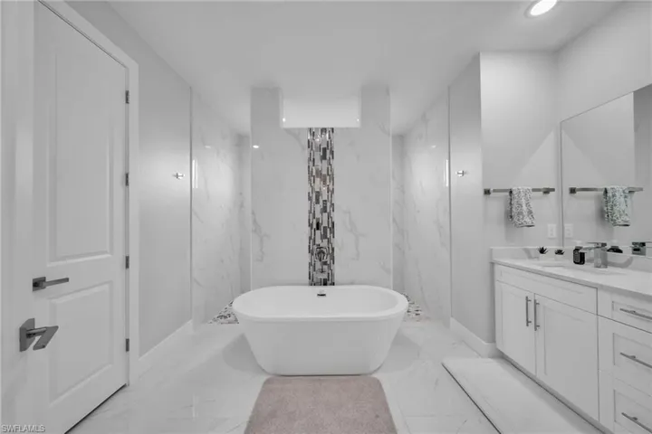 Bathroom featuring vanity and separate shower and tub