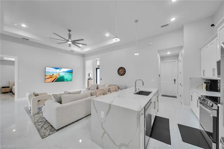 Living room with sink, a tray ceiling, and ceiling fan
