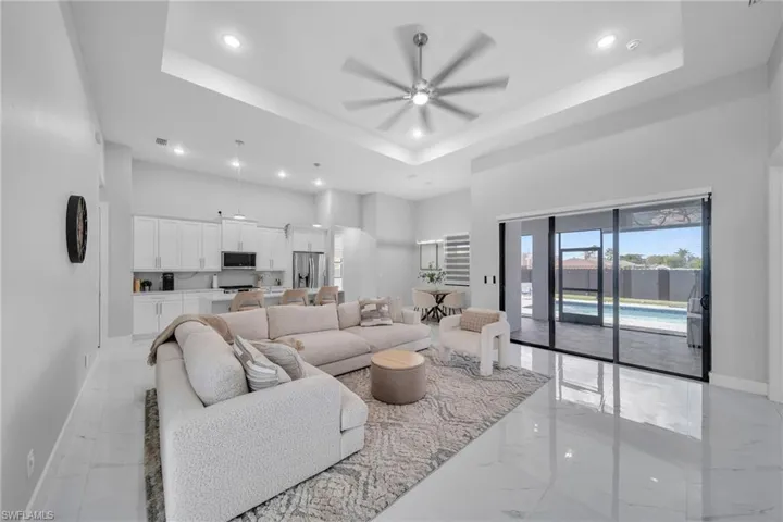Living room featuring a raised ceiling, a high ceiling, and ceiling fan