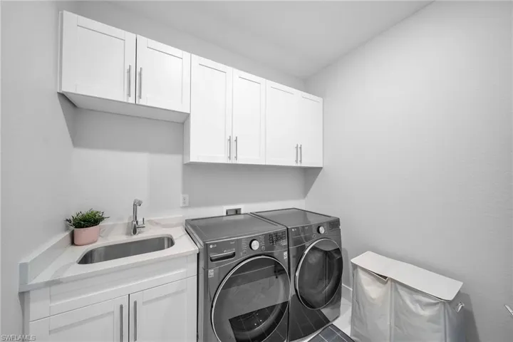 Laundry area with separate washer and dryer, sink, tile patterned flooring, and cabinets