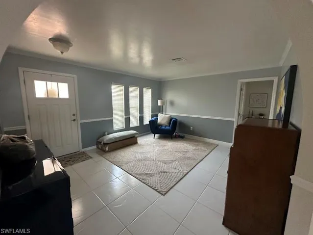 Tiled foyer entrance featuring crown molding and baseboards