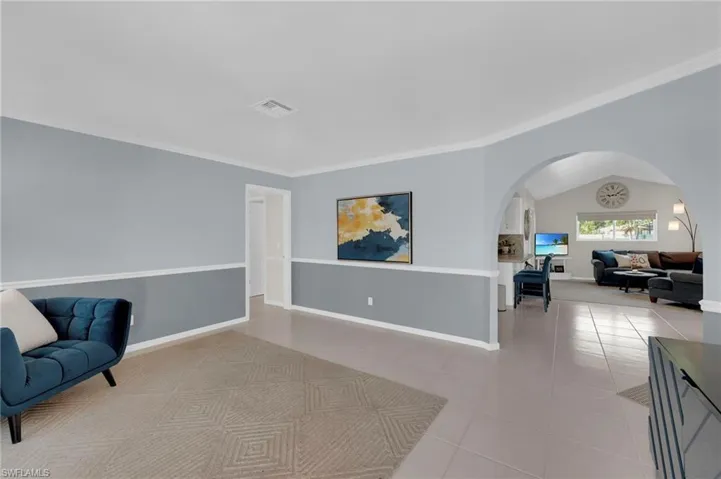 Sitting room with arched walkways, tile patterned flooring, and crown molding