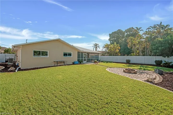Back of house featuring an outdoor fire pit, stucco siding, a sunroom, and a fenced backyard