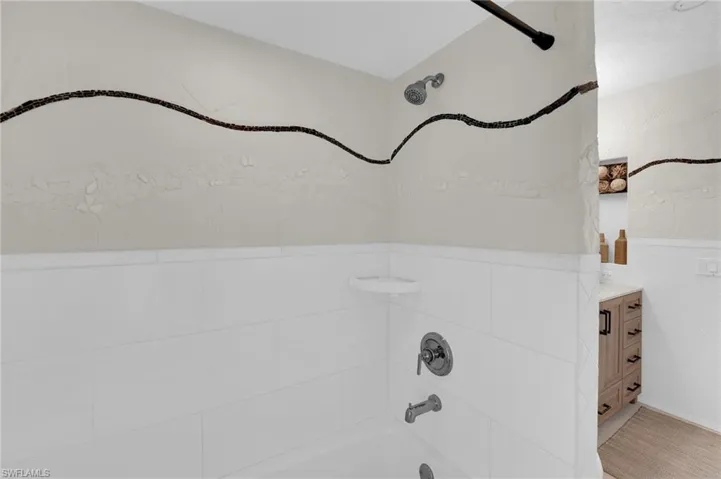 Full bath with bathing tub / shower combination, vanity, and tile walls