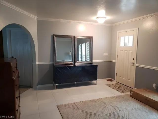 Tiled foyer entrance featuring arched walkways and crown molding
