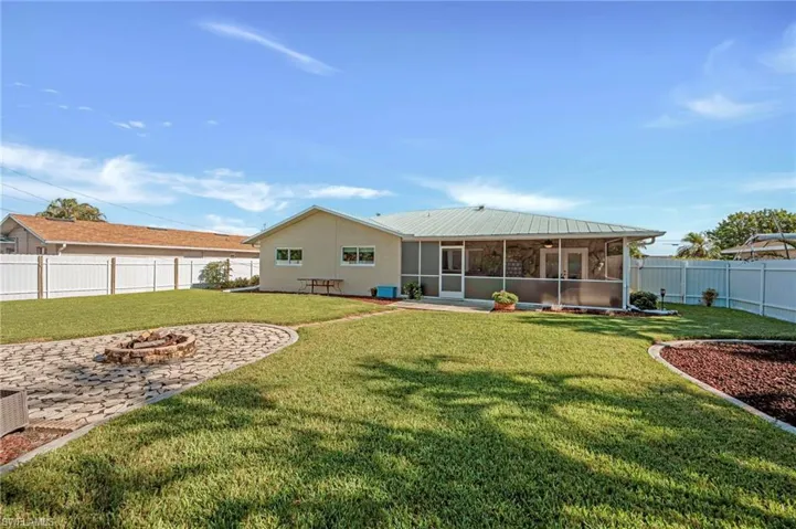 Rear view of house with a sunroom, a fire pit, a metal roof, a fenced backyard, and stucco siding