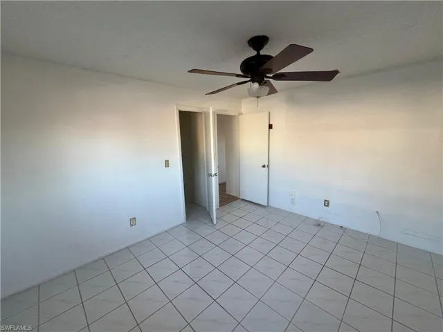 Spare room featuring a ceiling fan, light tile patterned floors, and a textured ceiling