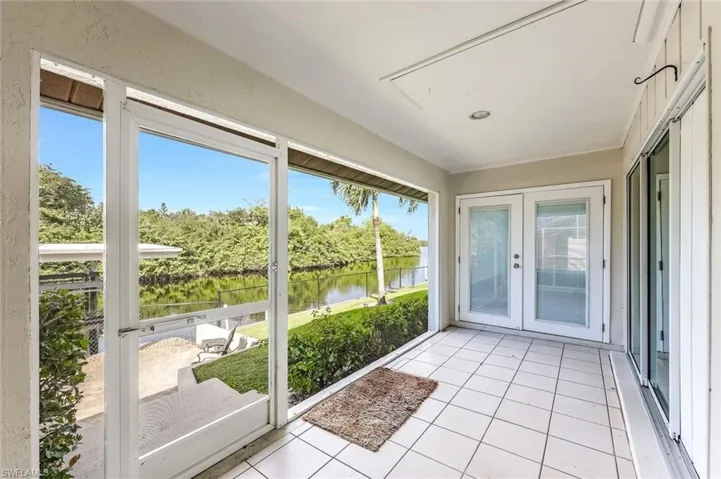 Unfurnished sunroom with french doors, a water view, and vaulted ceiling
