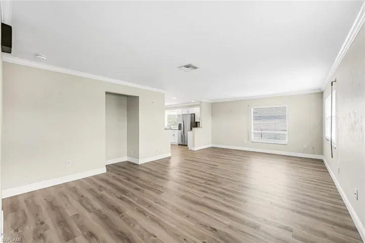 Unfurnished living room featuring light hardwood / wood-style floors and ornamental molding