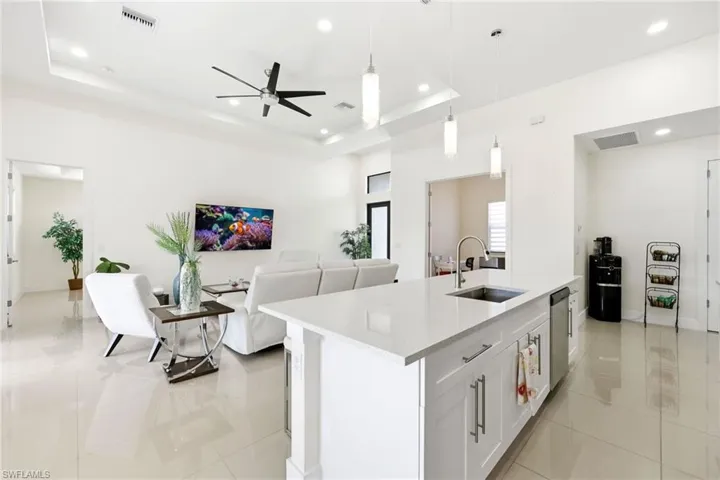Kitchen featuring open floor plan, a center island with sink, white cabinetry, pendant lighting, and light tile patterned flooring