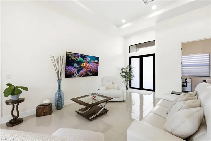 Living room featuring light tile patterned floors, recessed lighting, a high ceiling, and french doors