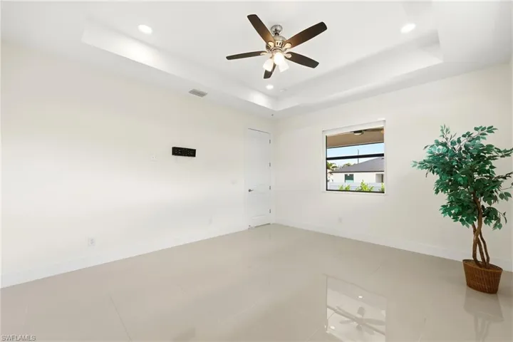 Unfurnished room with ceiling fan, recessed lighting, light tile patterned flooring, and a tray ceiling