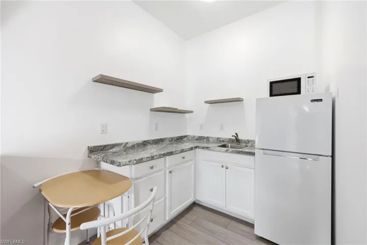 Kitchen featuring white appliances, open shelves, white cabinets, and wood tiled floors