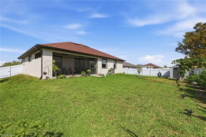 Back of house featuring a shed, a fenced backyard, stucco siding, and a sunroom