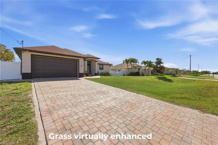 View of front of home with decorative driveway, an attached garage, and stucco siding