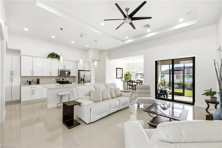 Living room featuring a ceiling fan, a raised ceiling, recessed lighting, and light tile patterned flooring