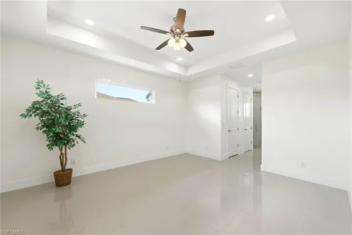 Spare room featuring a ceiling fan, recessed lighting, light tile patterned floors, and a tray ceiling